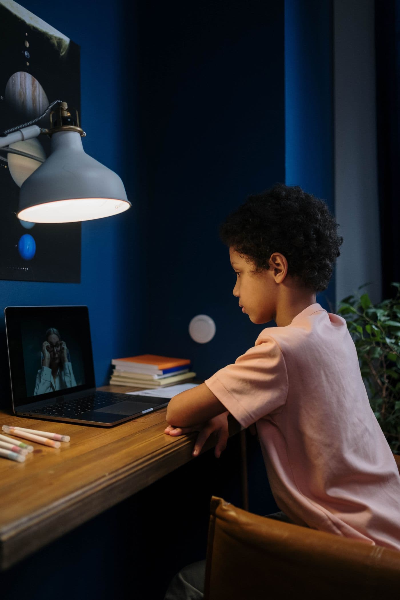 A student learning online in a warmly lamp-lit room at night