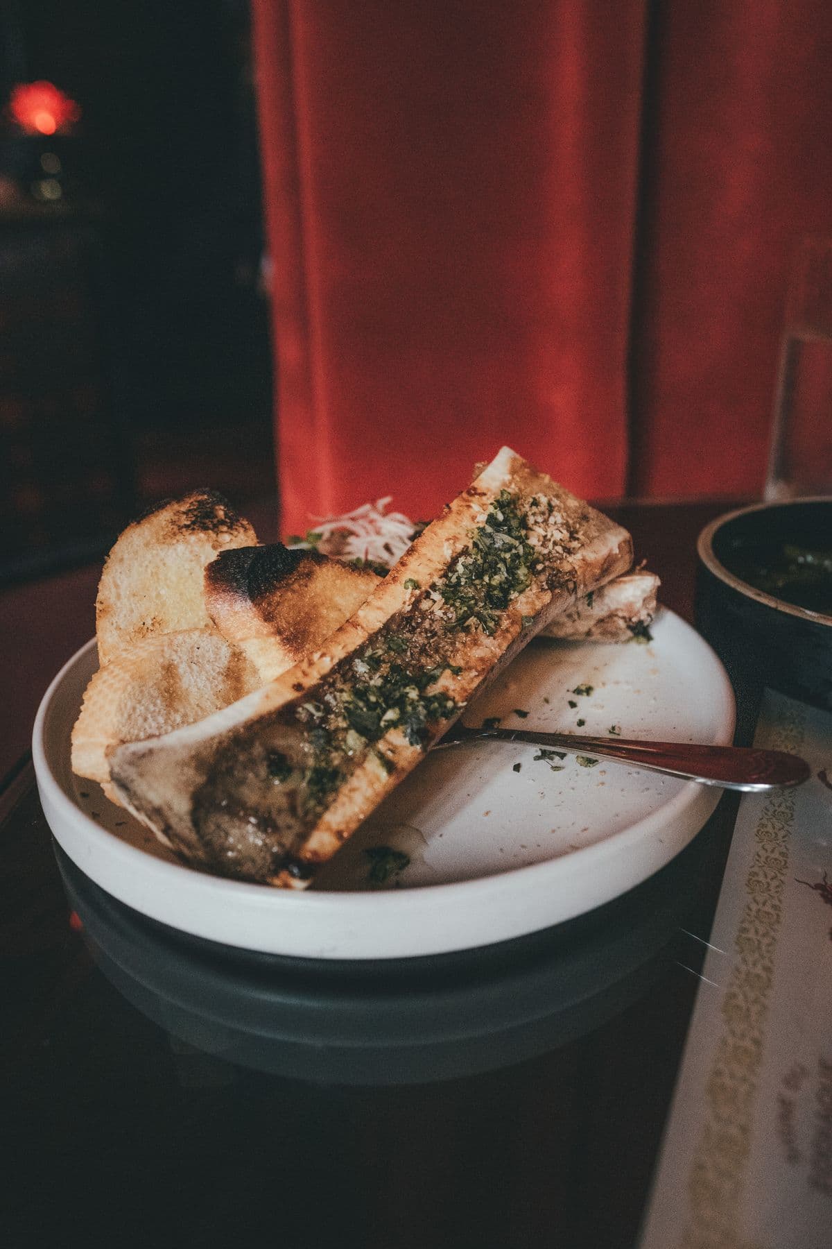 Roasted bone marrow served with crispy toast on a ceramic plate