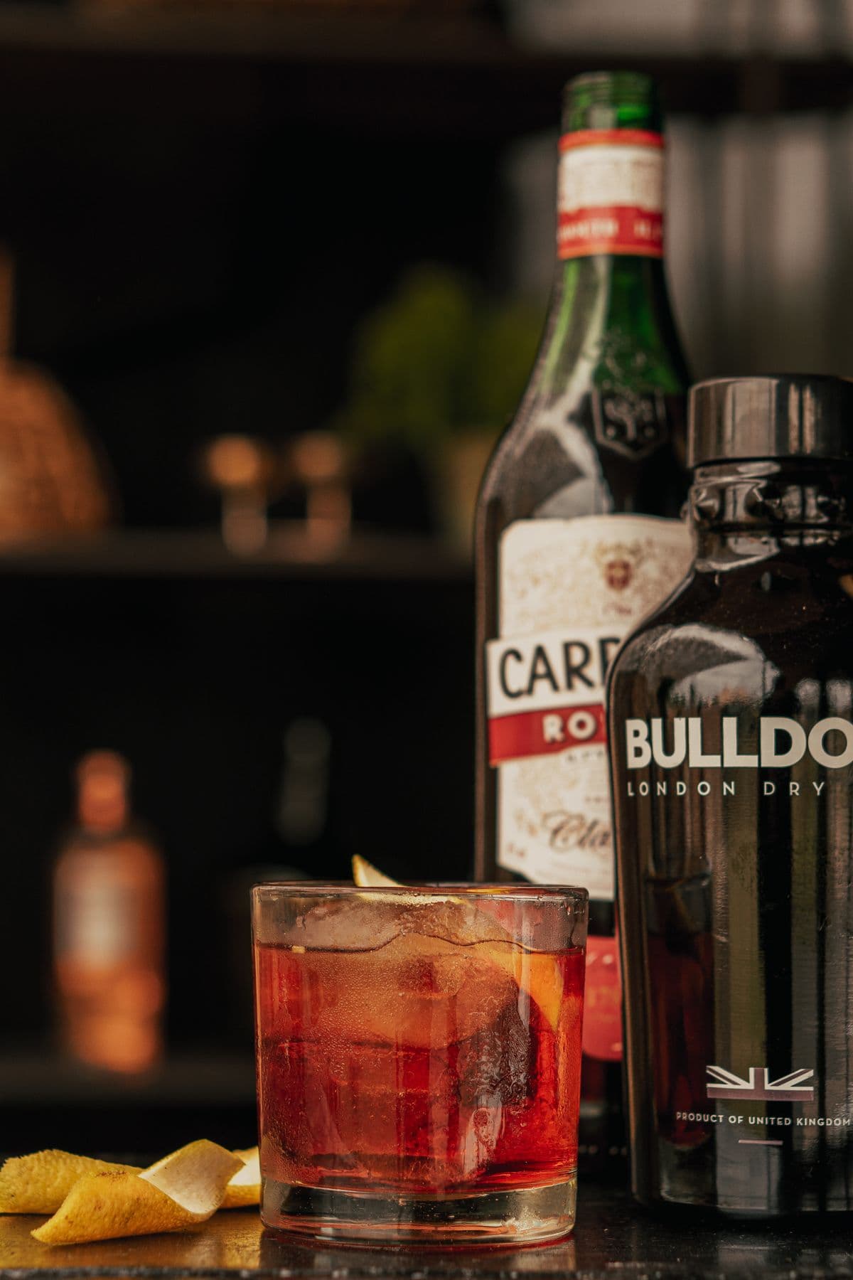 Cocktail on a moody bar counter with backlit bottles