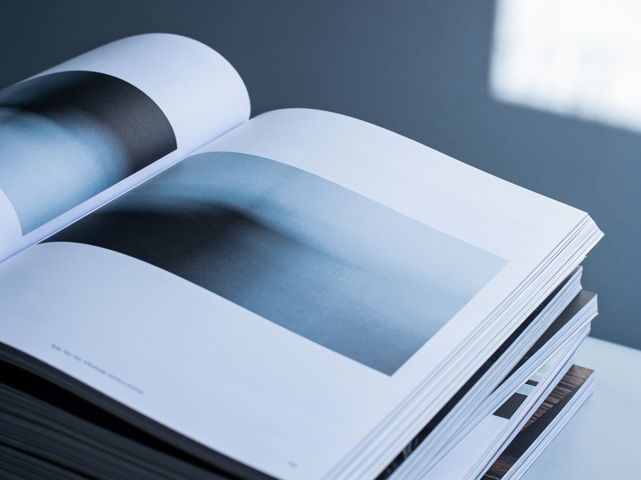 Open magazine with slate-blue duotone photography spreads