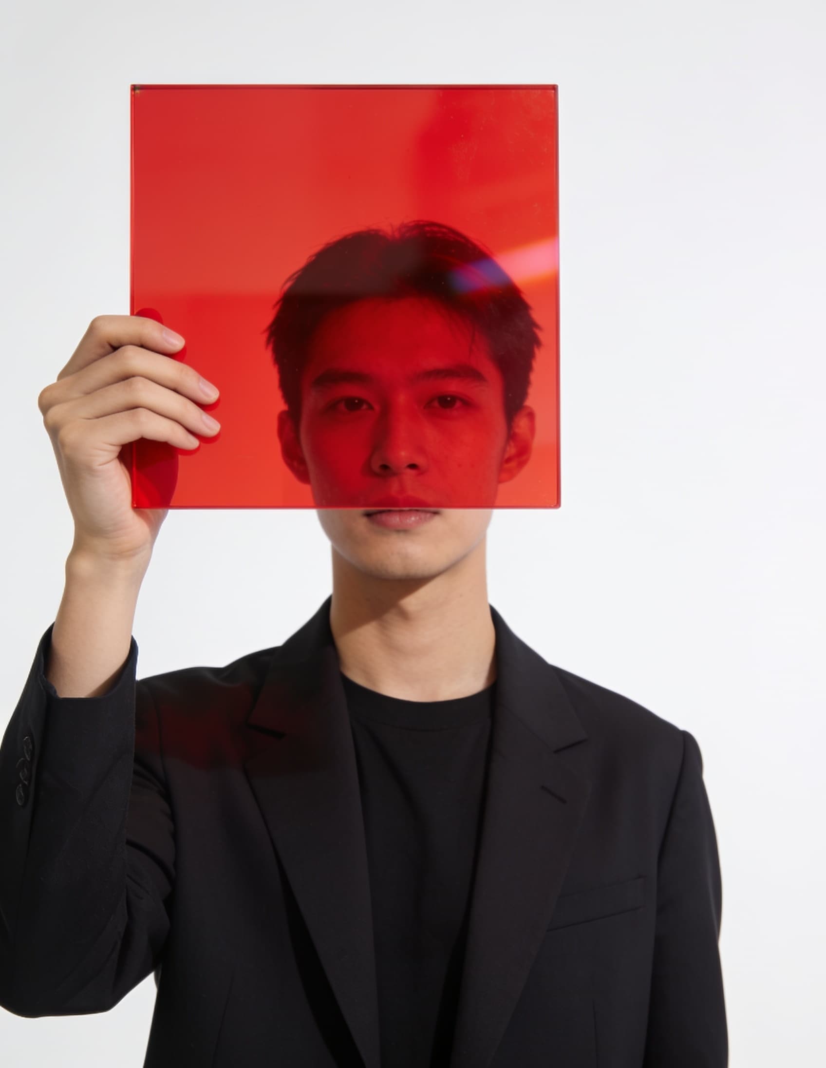 Ria Hossain in the studio, holding a red acrylic square