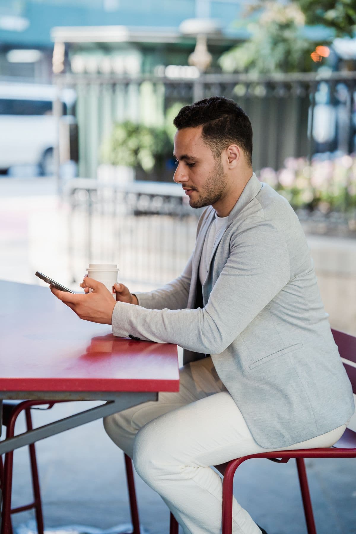 A café owner texting on his phone at an outdoor table