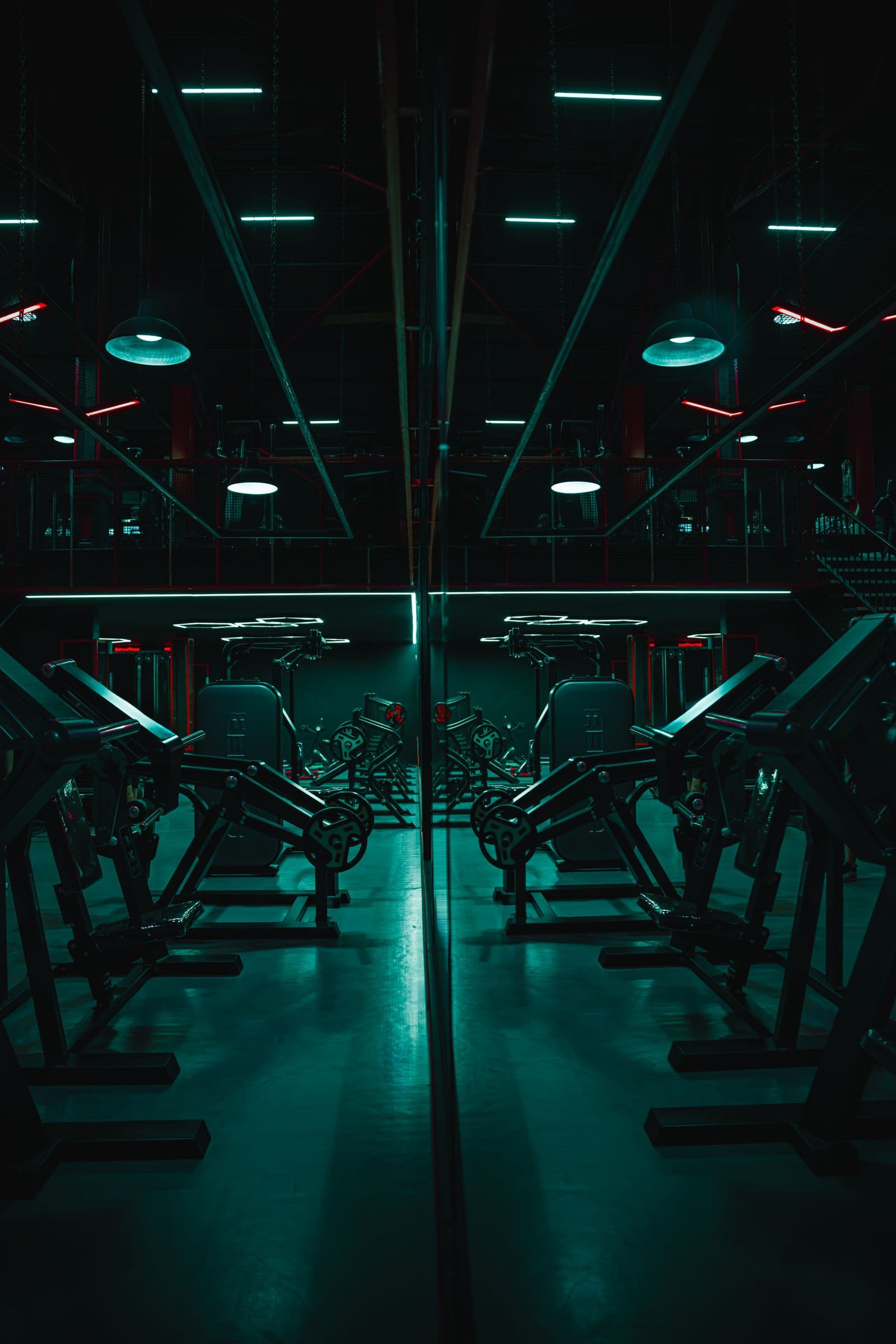 Dark gym floor with mirrored machines and neon light