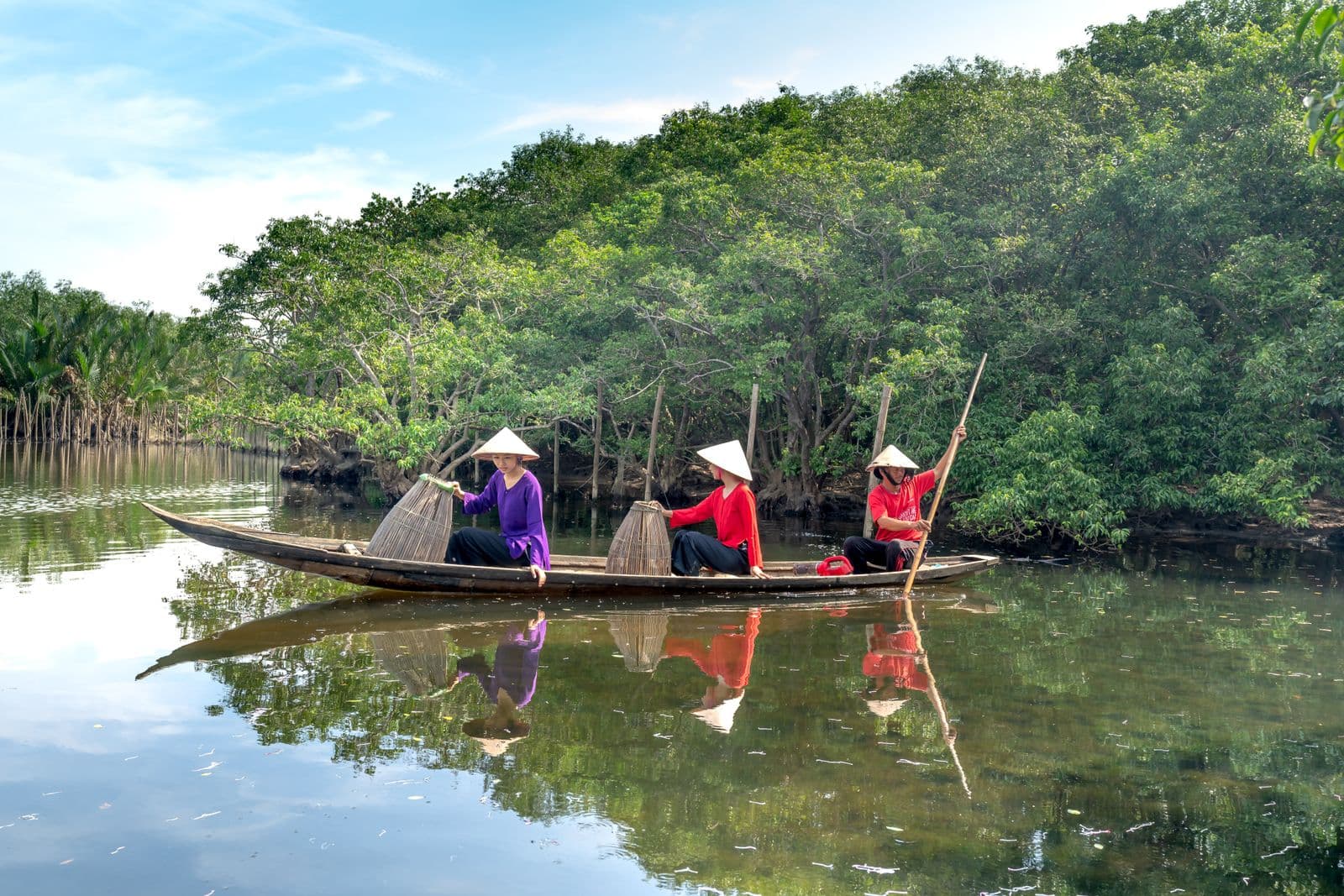 Fishermen navigating a mangrove river by wooden boat